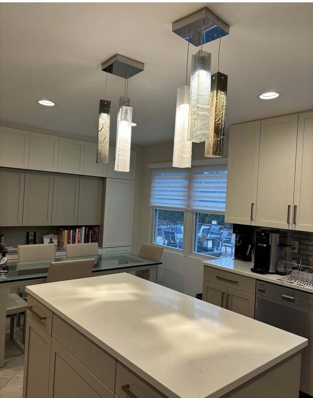 Minimalist kitchen with quartz island and sculptural glass pendant lighting, designed by Aviva Interior Design